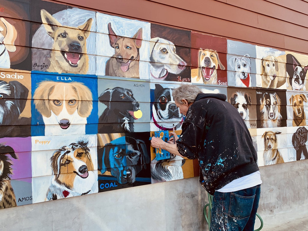 Arlington-based artist Patrick Kirwin painting the Dogs of Del Ray mural outside Stomping Ground.